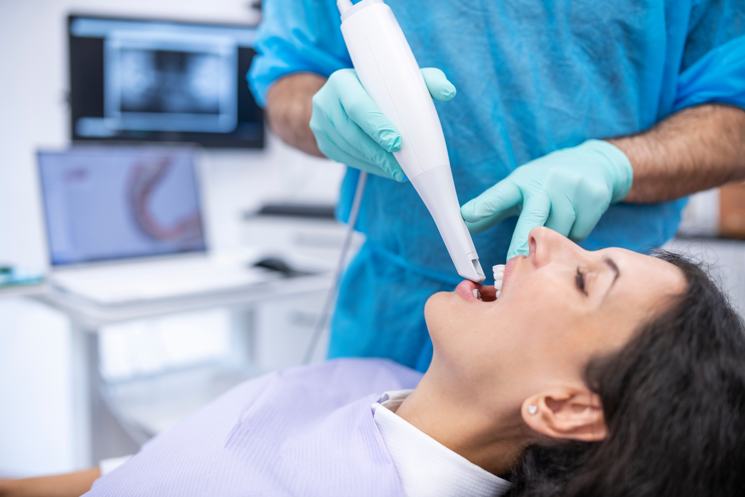 Orthodontist scanning patient with dental intraoral scanner.